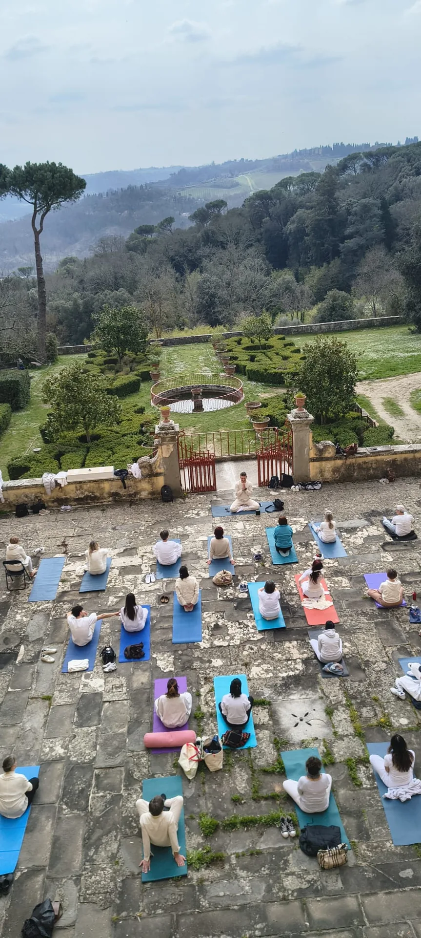 Meditazione di gruppo nel cortile di Villa Vrindavana, con vista sui giardini e sulle colline del Chianti
