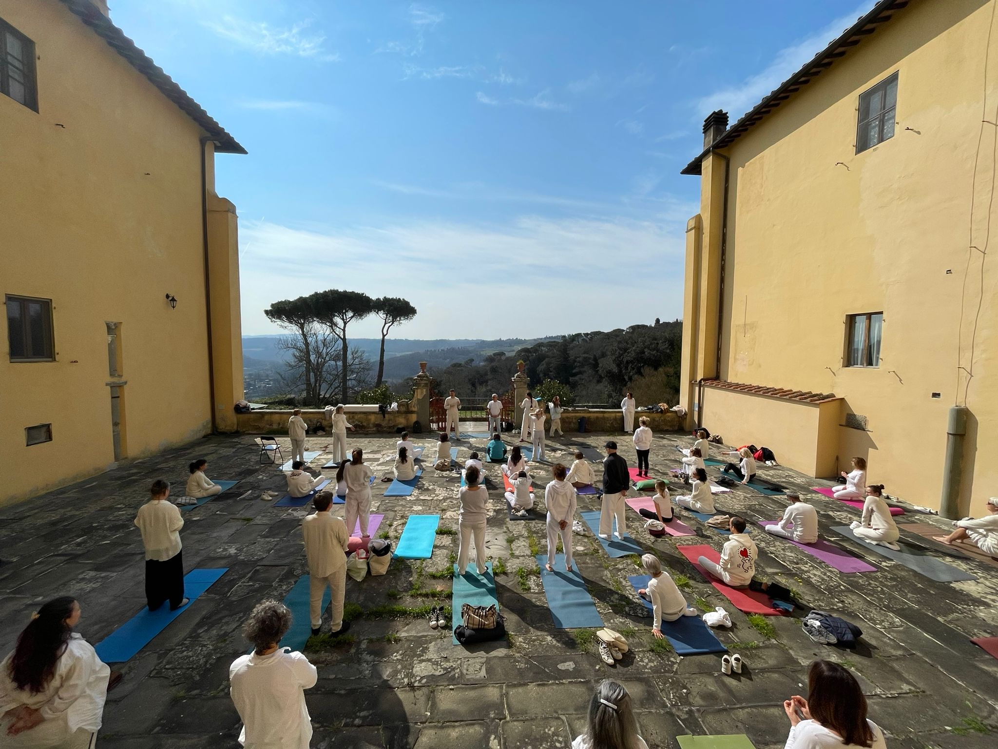 Partecipanti sui tappetini nel cortile di Villa Vrindavana, affacciato sulle colline